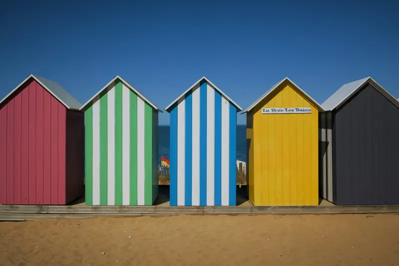 A row of brightly painted beach huts on the sand